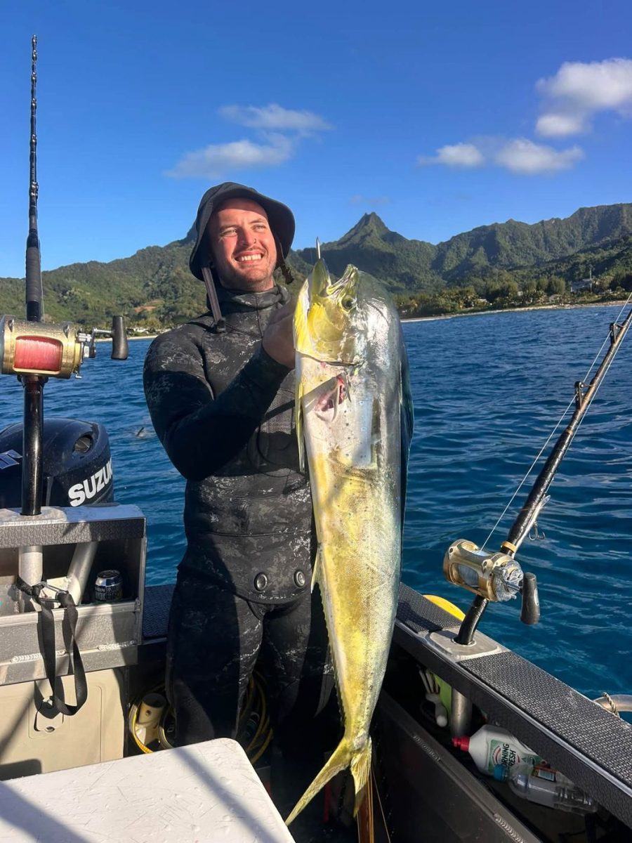 A diver in a wetsuit holding a mahi-mahi
